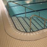Swimming pool overflow gratiing with bottom resin providing stability